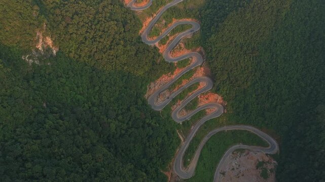 Aerial view of the curvy khau coc cha mountain pass road in vietnam. A beautiful snake like roadway winding through the lush green forest during sunset