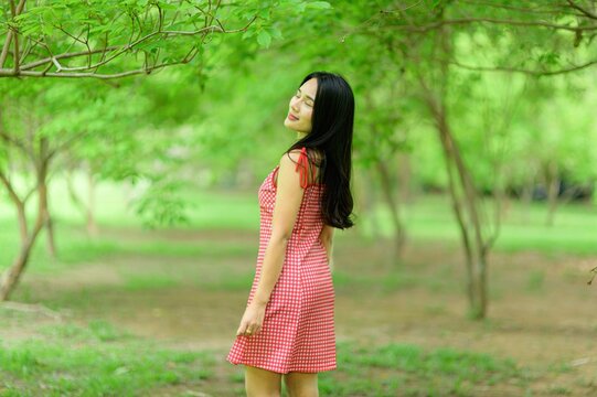 Woman in Red Dress Enjoying Nature in a Beautiful Flower Garden