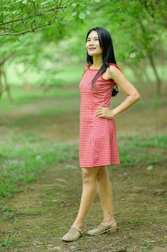 Woman in Red Dress Enjoying Nature in a Beautiful Flower Garden
