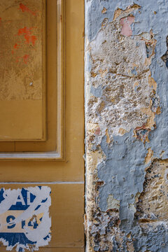 Weathered Yellow Wooden Door and Peeling Blue Paint Stone Wall, Distressed Surface Texture, Vintage Building Exterior