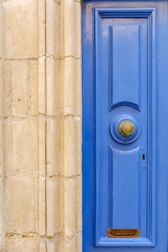 Blue wooden door with brass doorknob and weathered limestone wall