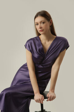 Elegant woman in purple satin midi dress posing in studio