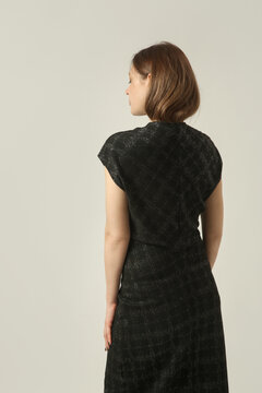 Fashion model wearing a black textured midi dress with a subtle sheen, V neckline and short sleeves, elegant and sophisticated contemporary fall style