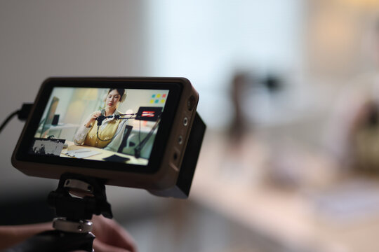 Woman recording podcast for online content creation. Woman wearing headphones and sitting at a desk, speaking into a microphone while recording a podcast or live stream.
