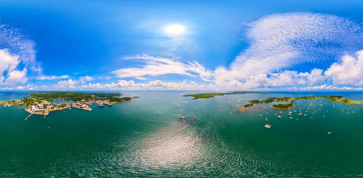 Aerial view of Woods Hole, featuring the harbor with boats and coastal landscape under a bright blue sky in Falmouth, Massachusetts, United States.