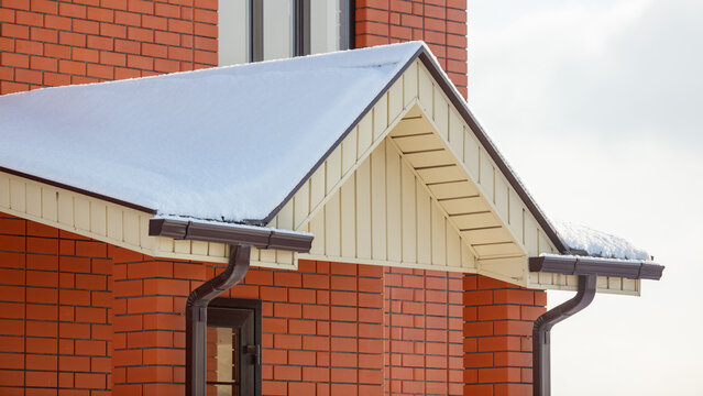 Snow rests gently on a house's gabled roof