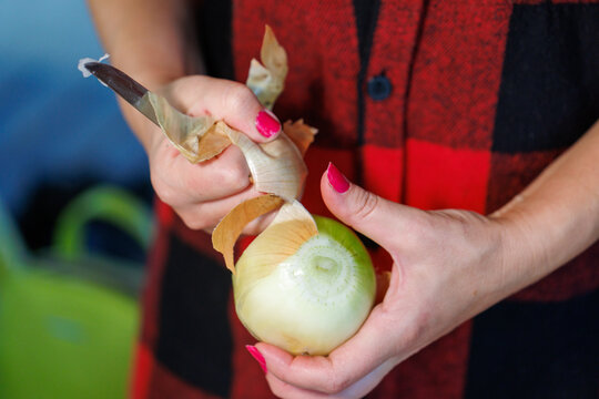 Woman peels onion with knife