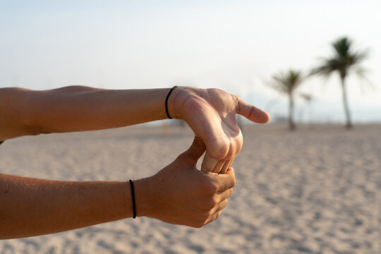 An athlete performing stretching exercises on a sandy beach before engaging in sports.