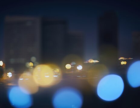 Blurred city lights at night with bokeh effect, urban skyline background with soft glowing circles