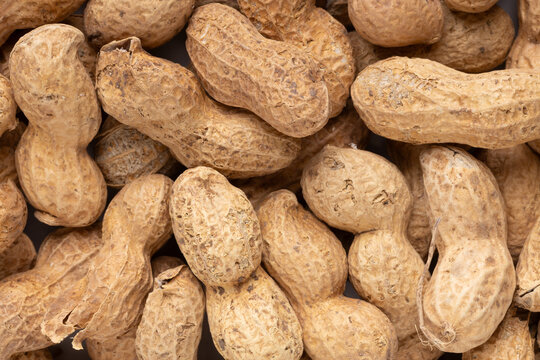 Overhead view of a dense pile of raw peanuts in hard textured shells, creating a natural organic background pattern related to agriculture, farming, and wholesome snacks.