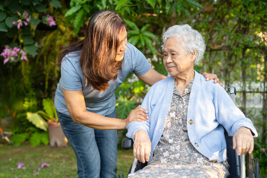 Asian elderly woman disability patient sitting on wheelchair in park.