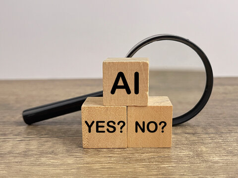 Wooden blocks displaying AI, YES, and NO beside a magnifying glass, representing artificial intelligence evaluation, decision making, fact checking, and the debate over emerging technology.