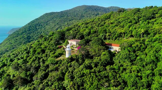 Daylight reveals a small lighthouse among the lush hills of Son Tra, with the blue sea beside Da Nang in central Vietnam