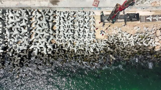 Aerial view of breakwater construction. Crane puts tetrapods on breakwater construction 