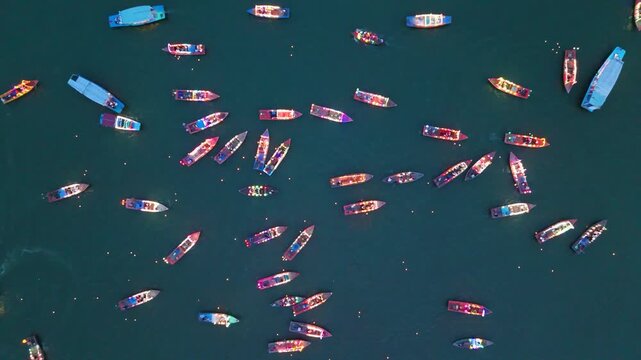 Dozens of colorful fishing boats float across deep blue water near Da Nang, Vietnam, forming a bright pattern in the calm daylight