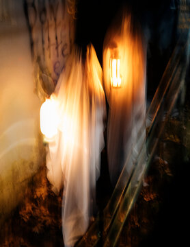 Ghost figures carrying lanterns at night during halloween