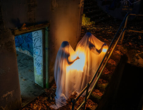 Ghostly figures illuminated on dark stairway with autumn leaves