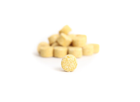 Isolated tea ball with defocused pile. Yellow lemon tea tablets. Alternative to loose leaf tea. Dissolves in hot and cold water. Selective focus.