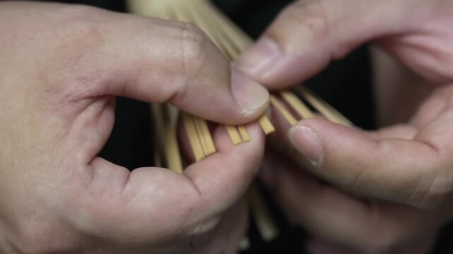 Extreme close up of fingers separating fine bamboo strips of a chasen tea whisk