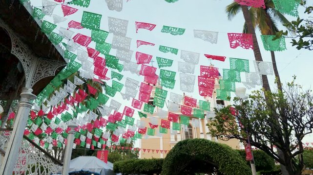 Mexican Papel Picado Hanging from a Garden Kiosk with Church in Background