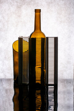 Figure made from a brown glass bottle and plastic pieces, set against a gray background