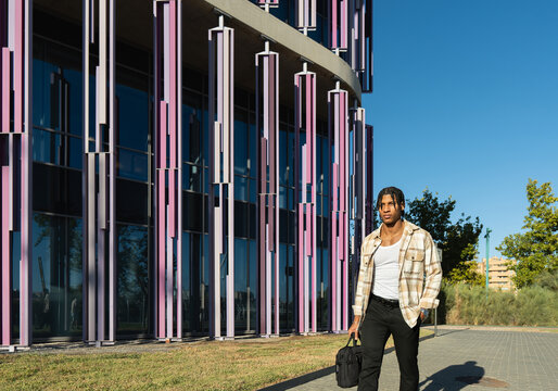 Young latino entrepreneur walking near modern office building
