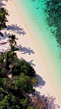 Aerial view of Port Barton Beach with white sand, turquoise water, palm trees, and lush tropical vegetation in Mimaropa, Philippines.