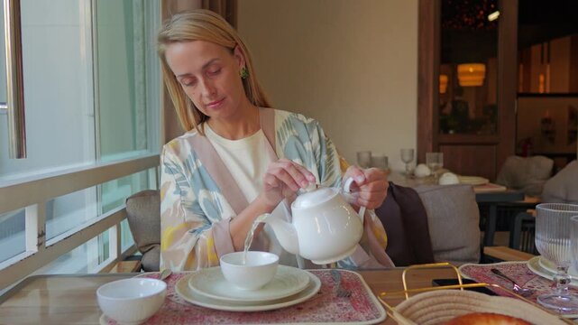 Woman serving tea at cafe table in Tashkent