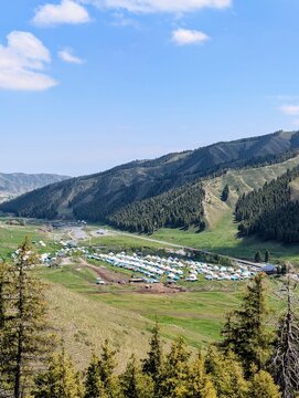 High angle view over yurt settlement in green mountain valley of Nalati grassland