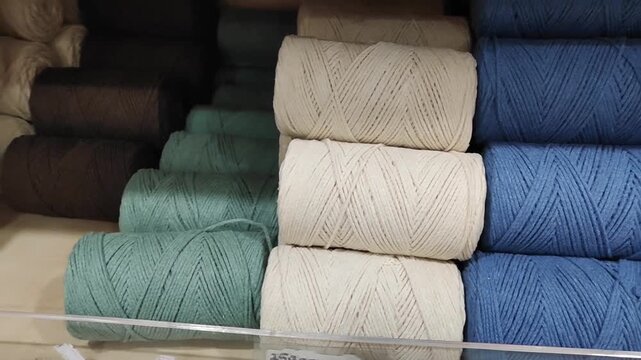 Colorful spools of thick macrame cord neatly arranged on a store shelf, durable cotton rope for knitting and handcrafting