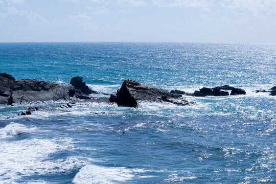 Dramatic Coastal Rocks and Deep Blue Ocean Waves under Bright Sunlight