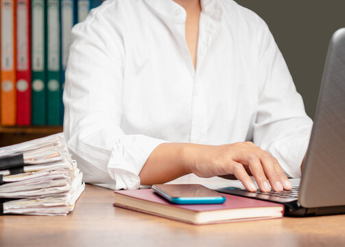 Person typing on laptop at office desk with documents