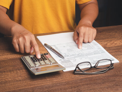 Person using calculator beside documents at desk  