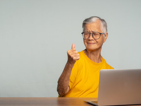 Senior woman giving thumbs up while using laptop