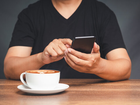Person using smartphone with coffee cup on table 