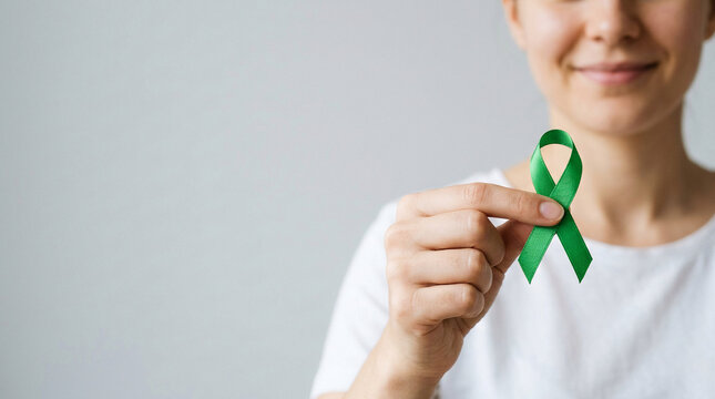 A woman holds a green ribbon, symbolizing mental health awareness, advocating for support, empathy, and hope for emotional well-being