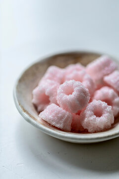 Pink sugar curls coated with granulated sugar in a white ceramic bowl