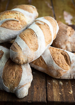 Rustic handmade loaves of bread on wooden table