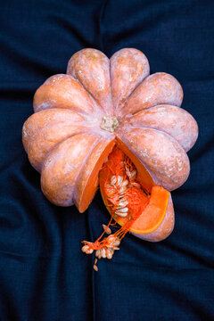 Cut Pumpkin showing seeds and orange flesh on blue dark blue fabric