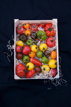 Wooden box with colorful heirloom tomatoes on straw packing
