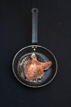 Fried pork chop with butter and rosemary in frying pan