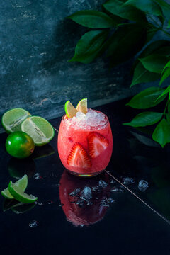 Strawberry-lime cocktail with crushed ice and lime wedges
