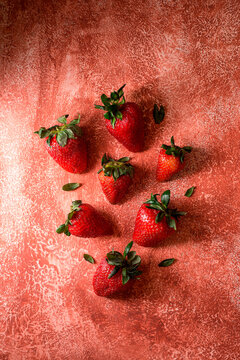 Fresh ripe strawberries on textured brick-red background