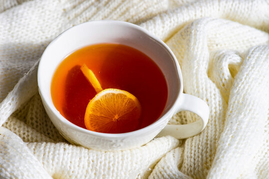 Cup of hot tea with lemon and white knitted sweater winter concept