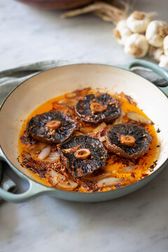Roasted portobello mushrooms cooking with onions and garlic in skillet