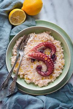 Lemon risotto with cooked octopus tentacles on green plate