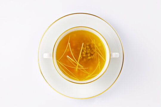 Chicken broth served in a white soup cup with a gold rim