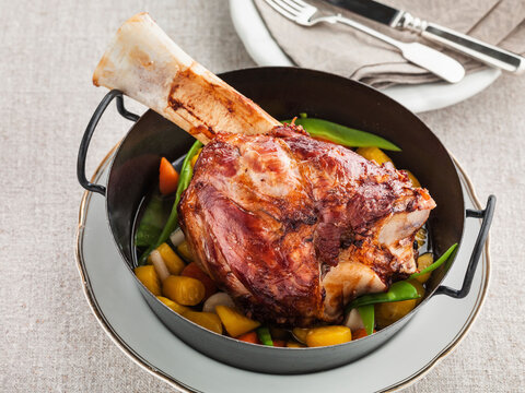 Bone-in veal knuckle on braised carrots and sugar snap peas