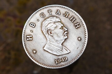 Close-up shot of a novelty souvenir coin featuring the profile portrait of Joseph Stalin with Cyrillic text and 1949 year, set against a blurred background © PhotoChur