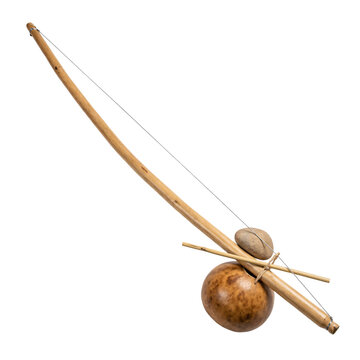 Brazilian berimbau musical bow with a curved wooden staff, a taut wire, a gourd resonator and a stone and stick, isolated on transparent background